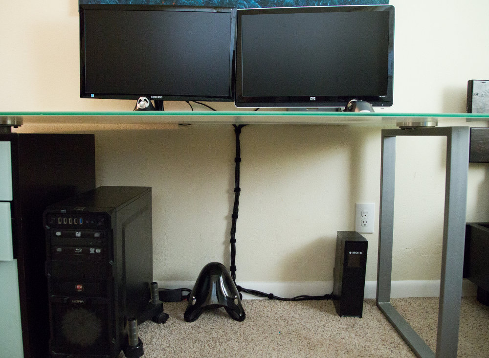 Desk with two monitors on it with good cable management underneath with cable ties organizing cables under desk and making cords look neat.